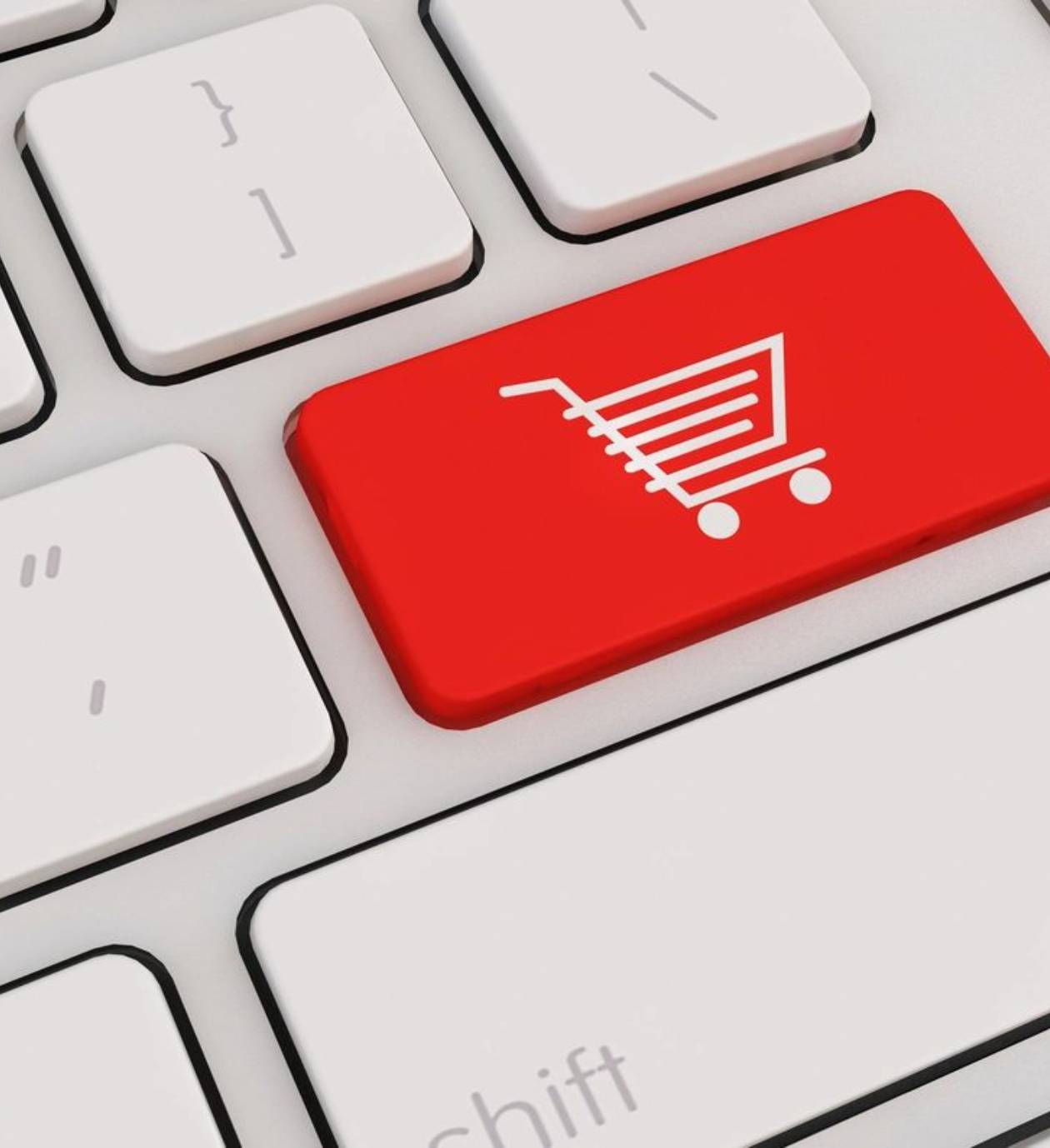 Red shopping cart key on a white keyboard indicating online shopping.