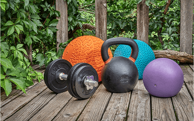 Weights and exercise balls on wooden deck.