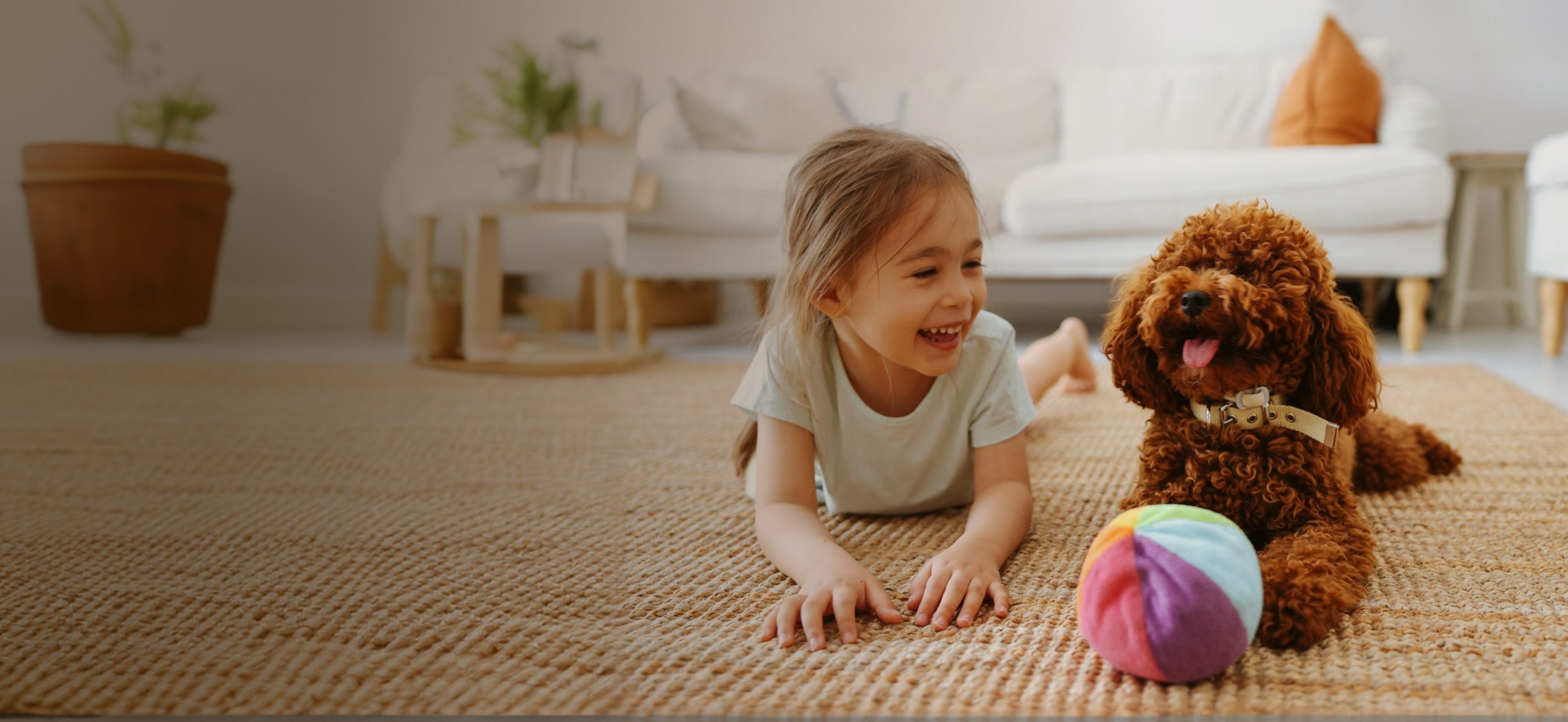 Girl and dog playing with colorful ball.